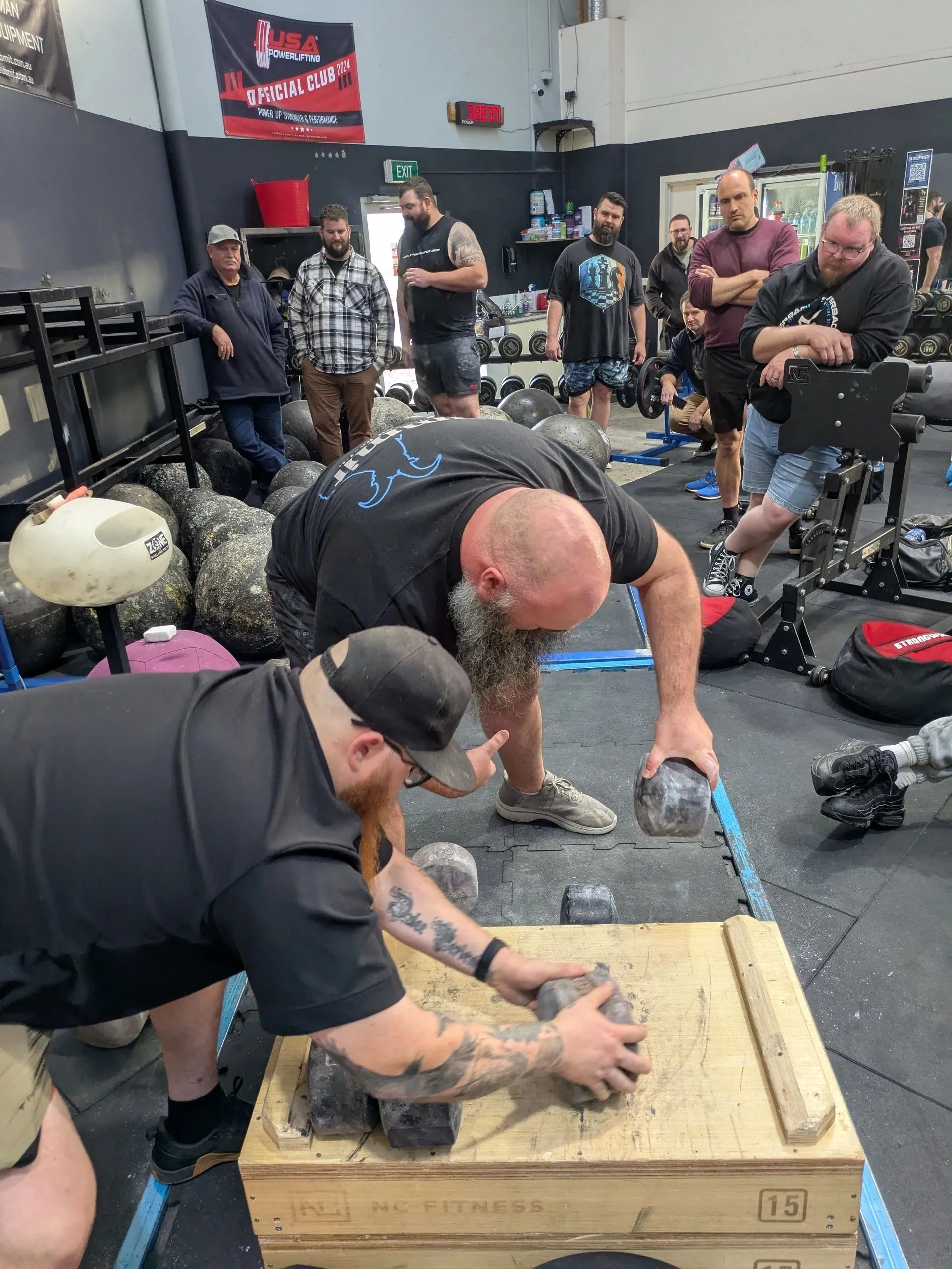 Refereeing and official implement lift - competitor lifting block weights under official supervision