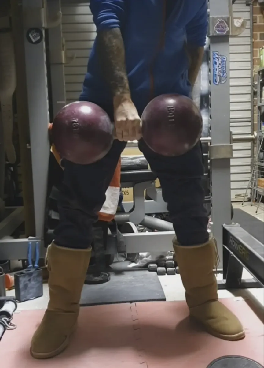 Tom Denmeade lifting the 78kg Holle Thomas Inch Dumbbell replica in iconic Ugg boots